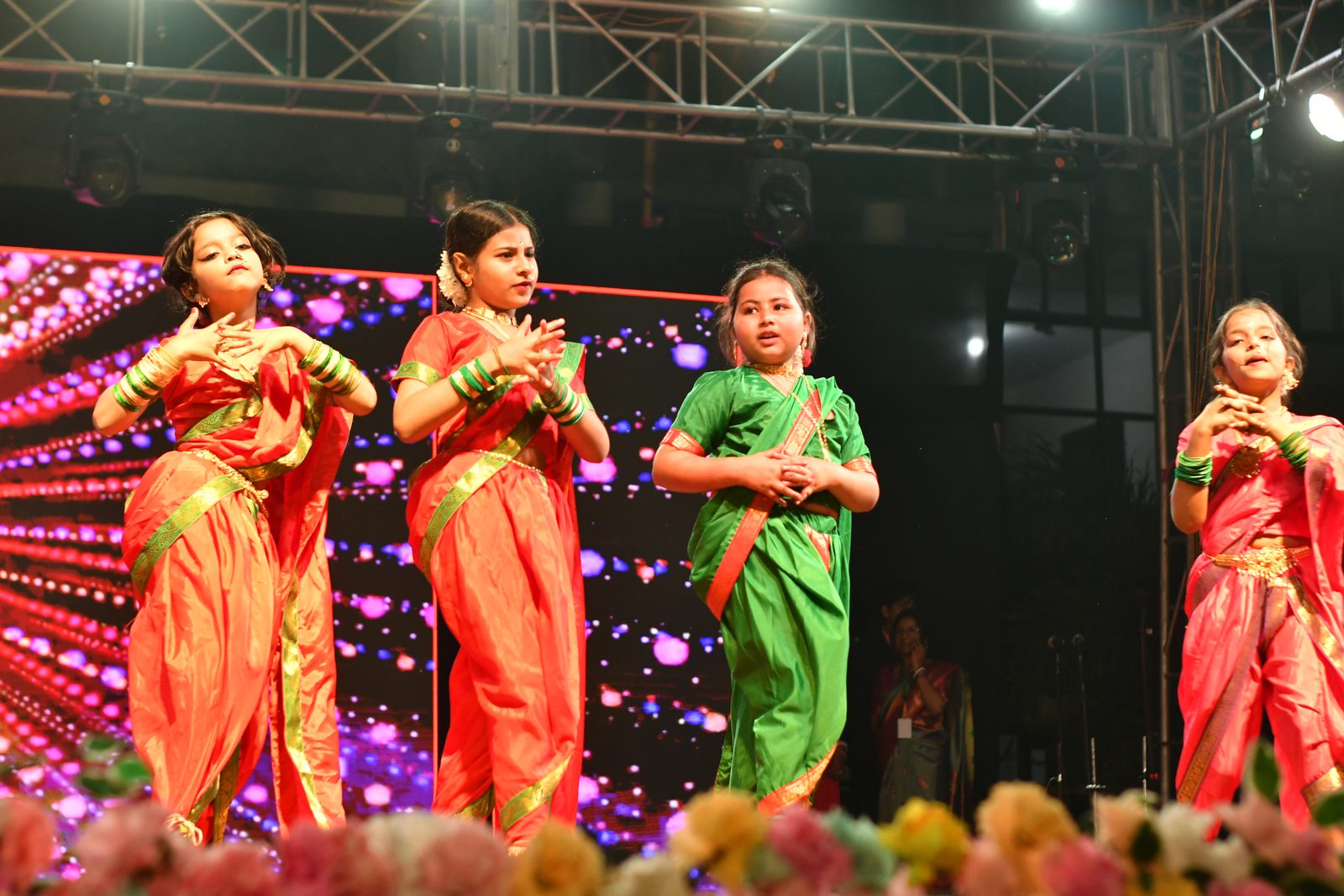 Girls in traditional saris performing a folk dance on stage