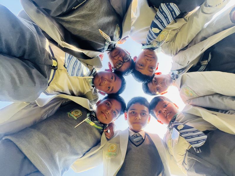 Students in a huddle, smiling down at the camera
