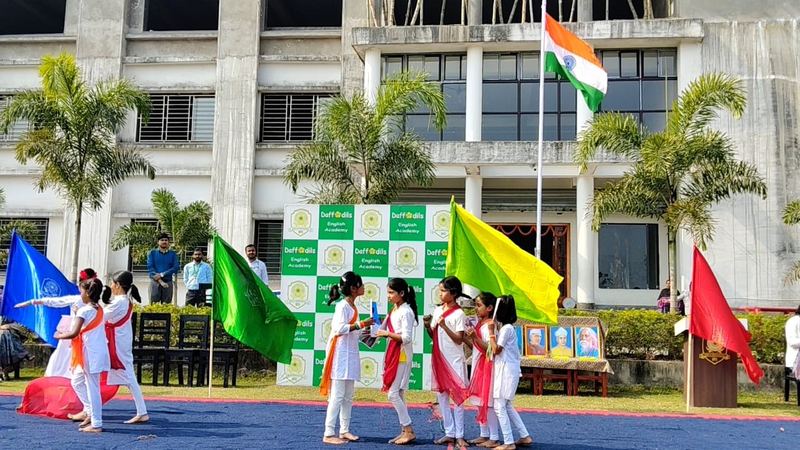 Students performing a flag dance in front of the school building